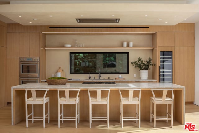 kitchen with a kitchen island, appliances with stainless steel finishes, wine cooler, and a breakfast bar