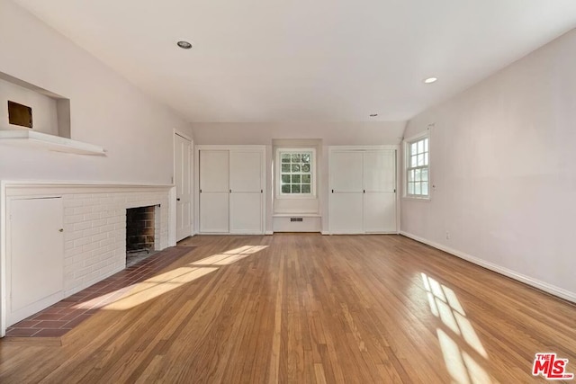 unfurnished living room with a brick fireplace and hardwood / wood-style floors