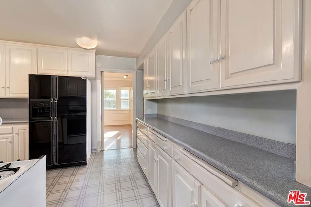 kitchen featuring white cabinets and black fridge