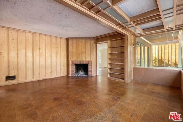 unfurnished living room with a fireplace and wooden walls