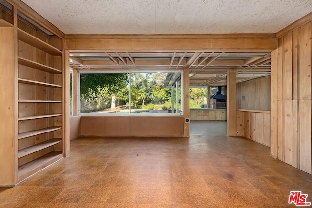 empty room featuring a wealth of natural light, built in features, and wood walls