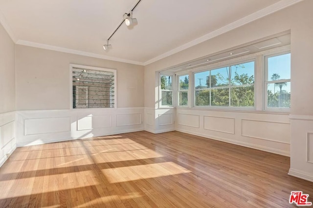 unfurnished room with crown molding, track lighting, and light hardwood / wood-style flooring