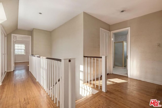 corridor with light hardwood / wood-style flooring and lofted ceiling