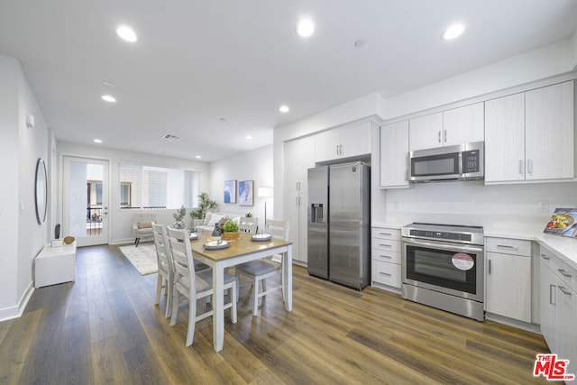 kitchen with appliances with stainless steel finishes, dark wood-type flooring, and white cabinets