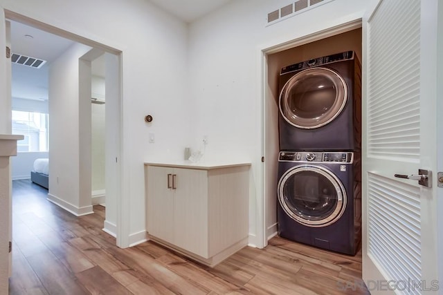 washroom featuring stacked washer and clothes dryer and light hardwood / wood-style floors