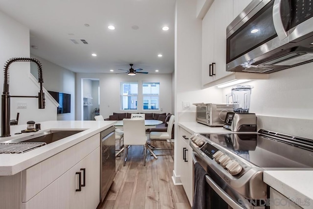 kitchen featuring white cabinets, appliances with stainless steel finishes, light hardwood / wood-style flooring, and sink