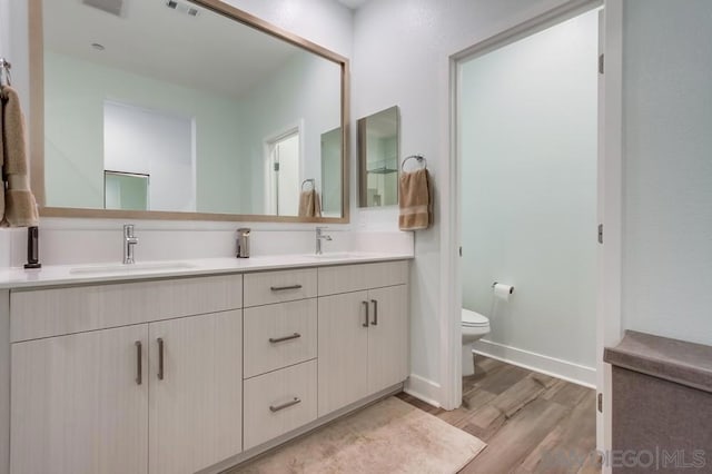 bathroom with toilet, vanity, and hardwood / wood-style flooring