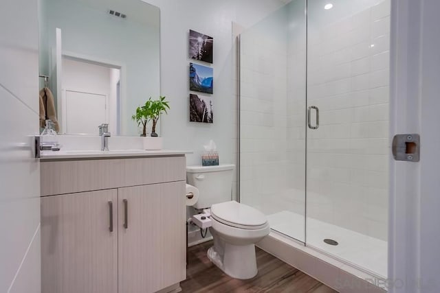 bathroom with toilet, hardwood / wood-style flooring, walk in shower, and vanity