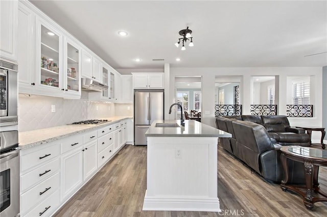 kitchen featuring sink, white cabinetry, appliances with stainless steel finishes, and a center island with sink