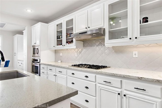 kitchen with decorative backsplash, white cabinets, appliances with stainless steel finishes, and light stone countertops