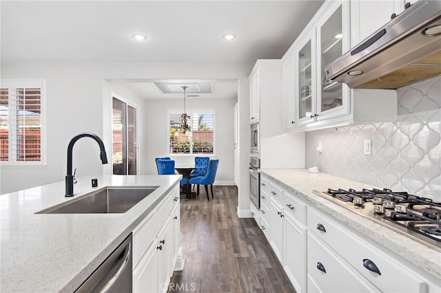 kitchen with decorative light fixtures, white cabinetry, stainless steel appliances, sink, and light stone counters