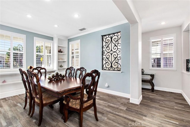 dining room featuring dark wood-type flooring, ornamental molding, and built in features