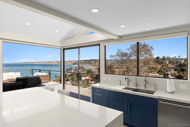 kitchen featuring stainless steel dishwasher, blue cabinets, sink, and a water view