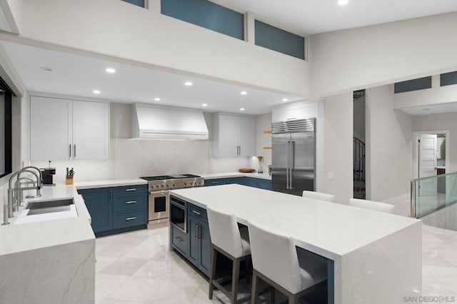 kitchen featuring blue cabinetry, built in appliances, a kitchen island, sink, and white cabinetry