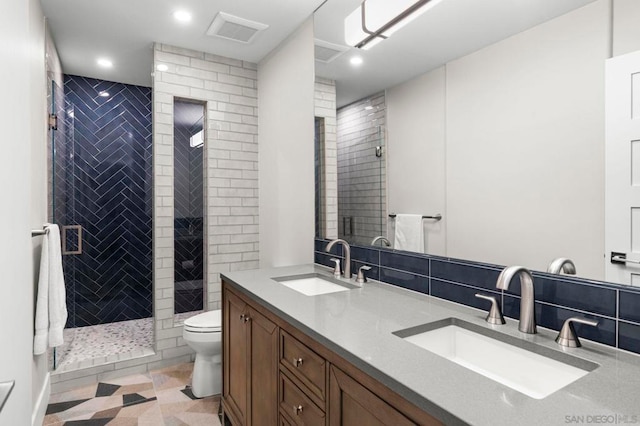 bathroom with tile patterned flooring, a tile shower, vanity, and toilet