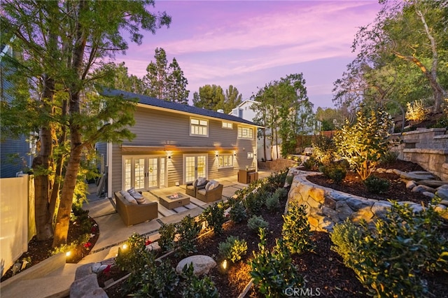 back house at dusk with a patio, french doors, and outdoor lounge area