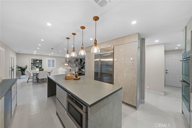 kitchen featuring built in appliances, pendant lighting, and a kitchen island