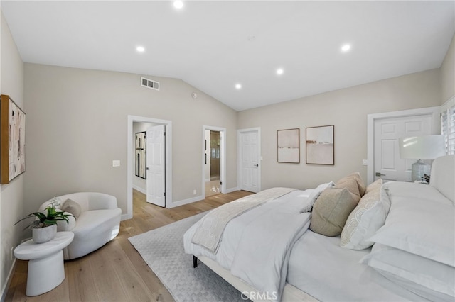 bedroom featuring light wood-type flooring, ensuite bathroom, and vaulted ceiling