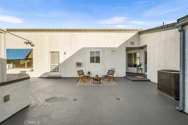 back of property featuring central air condition unit, a fire pit, and a patio