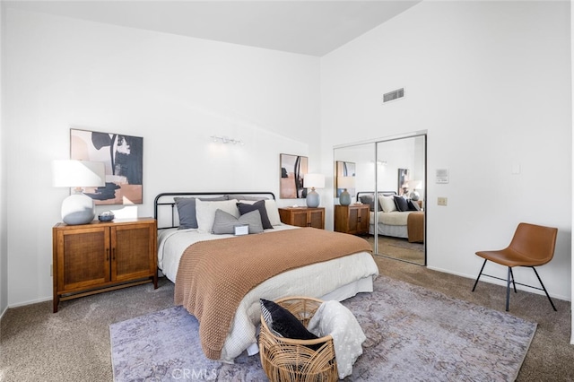 carpeted bedroom with a high ceiling and a closet