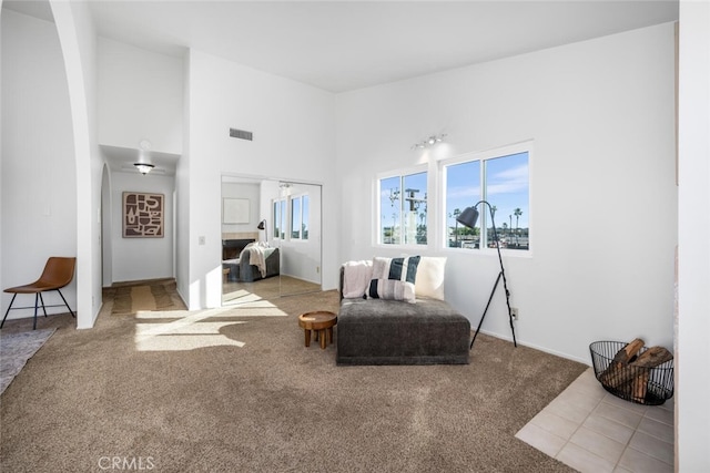 living room featuring a towering ceiling and light colored carpet