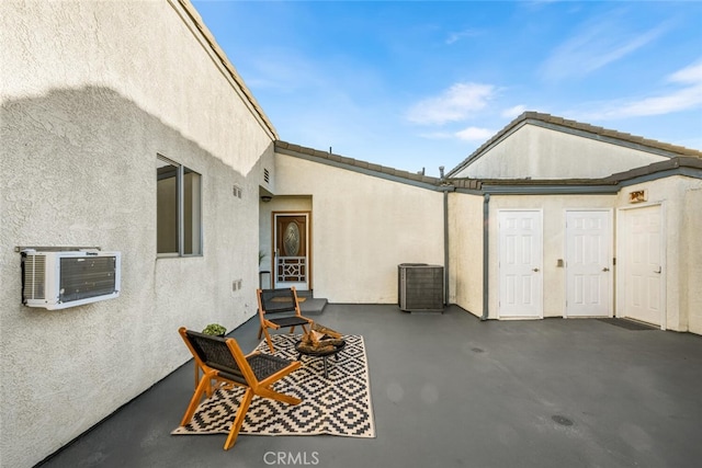 view of patio with a wall unit AC, central AC, and a fire pit