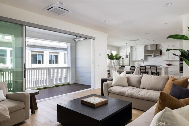 living room featuring sink and light hardwood / wood-style flooring