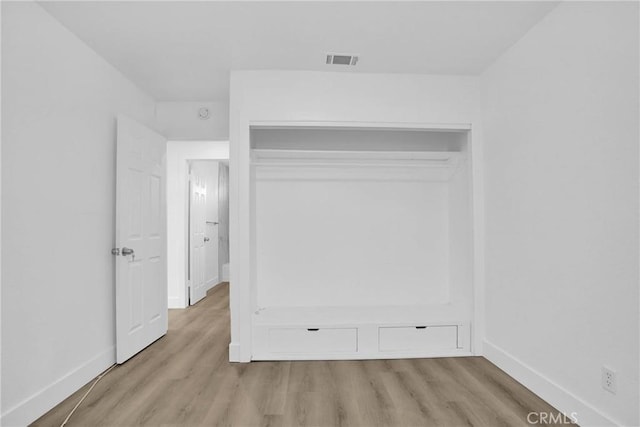 unfurnished bedroom with light wood-type flooring and a closet