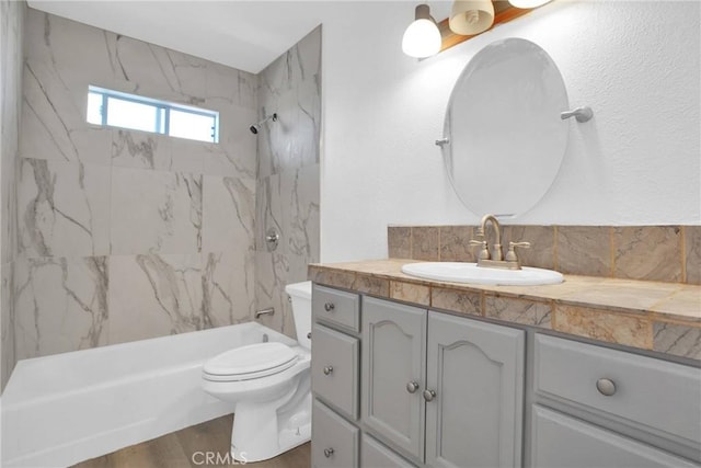 full bathroom with toilet, decorative backsplash, tiled shower / bath, wood-type flooring, and vanity