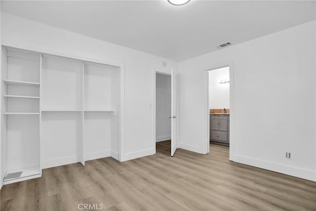 unfurnished bedroom with a closet, ensuite bath, and light hardwood / wood-style flooring