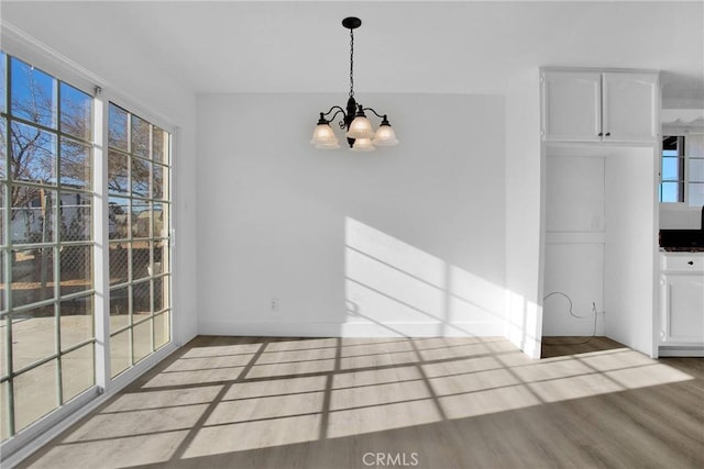 unfurnished dining area featuring a wealth of natural light, light hardwood / wood-style flooring, and a notable chandelier