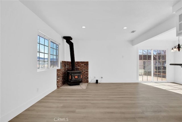 living room with a wood stove and light hardwood / wood-style flooring