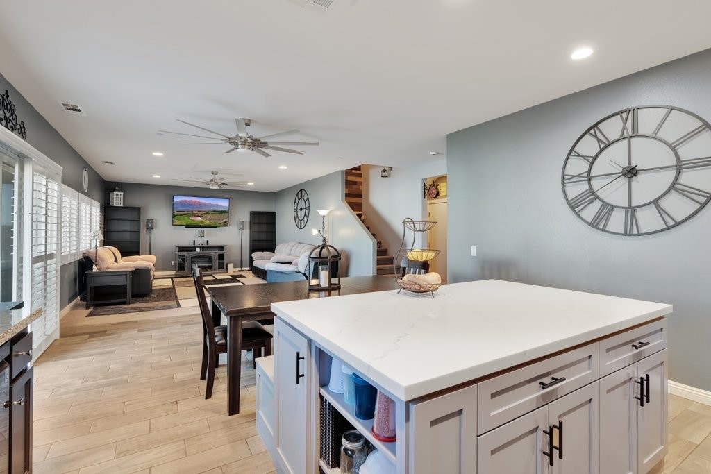 kitchen with a center island, light hardwood / wood-style flooring, ceiling fan, light stone countertops, and white cabinets