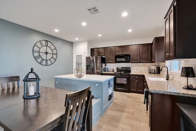 kitchen with sink, dark brown cabinetry, black appliances, a kitchen island, and decorative backsplash