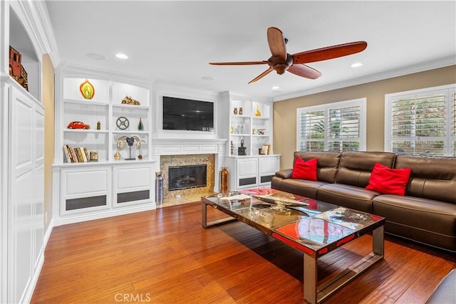 living room featuring a fireplace, ceiling fan, built in features, and ornamental molding