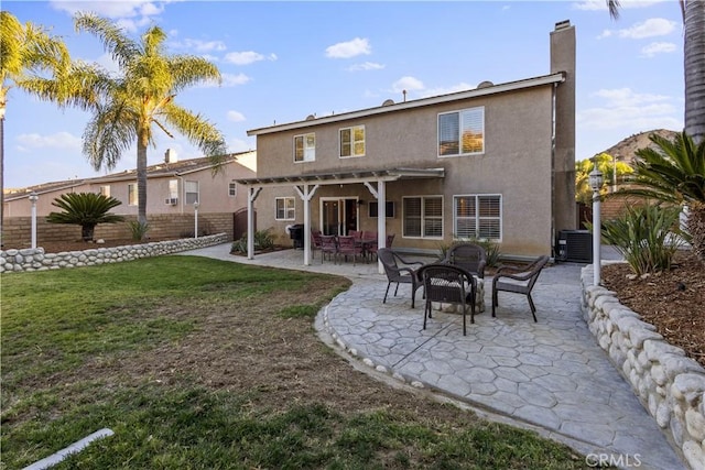 back of property with a pergola, a patio area, and a lawn