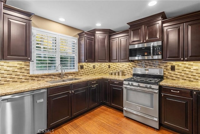 kitchen featuring appliances with stainless steel finishes, light hardwood / wood-style flooring, tasteful backsplash, and sink