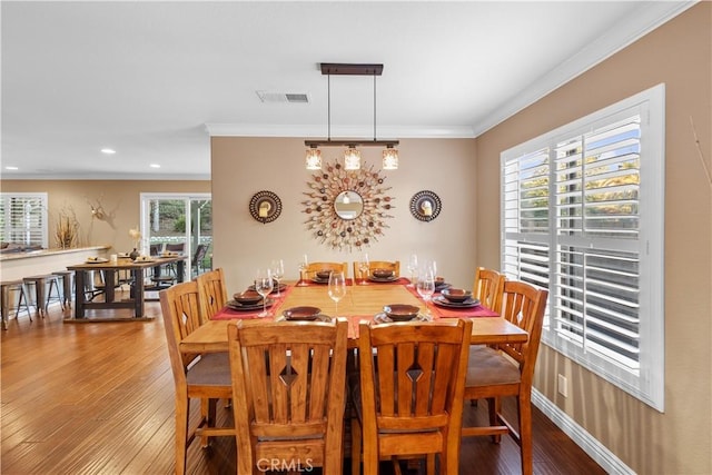 dining room featuring hardwood / wood-style flooring, ornamental molding, and plenty of natural light