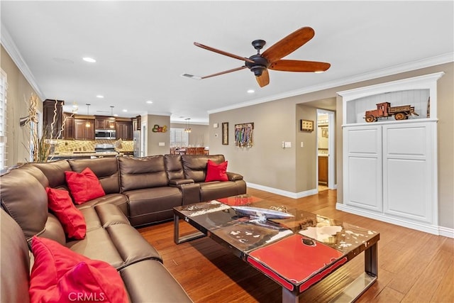 living room featuring ceiling fan, ornamental molding, and light wood-type flooring