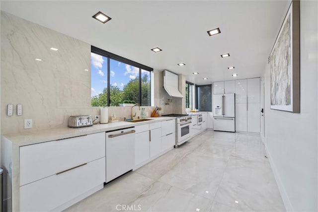 kitchen with sink, premium appliances, white cabinets, decorative backsplash, and custom exhaust hood