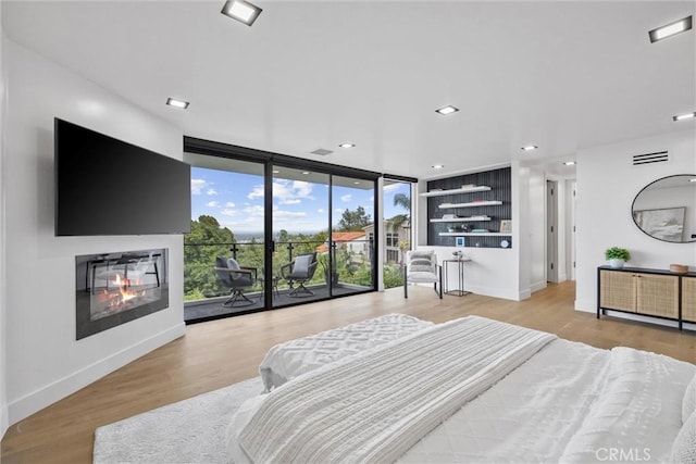 bedroom featuring access to outside, light hardwood / wood-style floors, and floor to ceiling windows