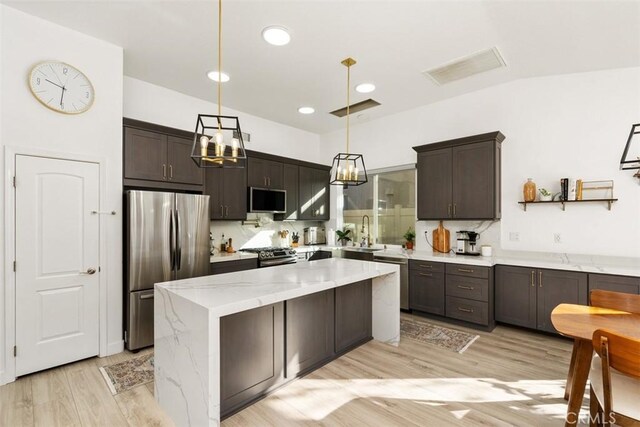 kitchen with hanging light fixtures, stainless steel appliances, a kitchen island, dark brown cabinets, and sink