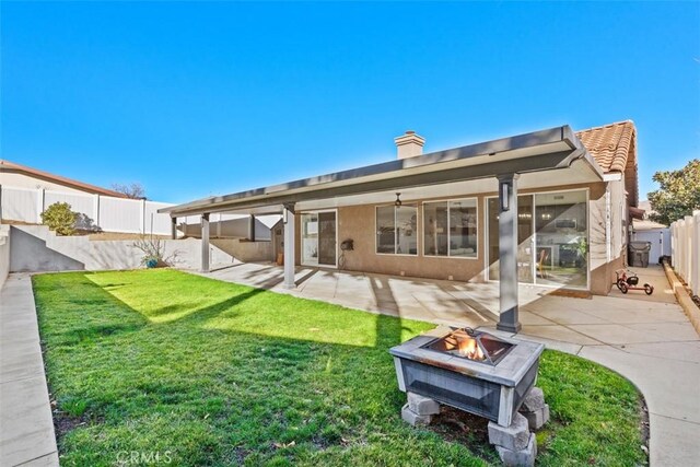 back of property with a patio area, a yard, and a fire pit