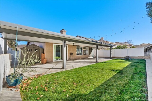 rear view of property with a yard, a storage shed, and a patio