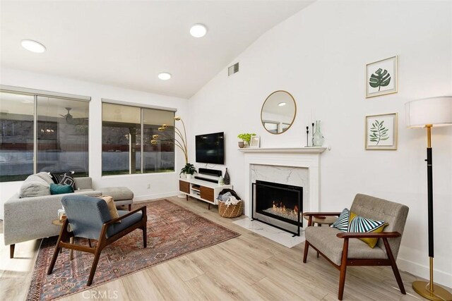 living room with lofted ceiling, a premium fireplace, and light hardwood / wood-style floors