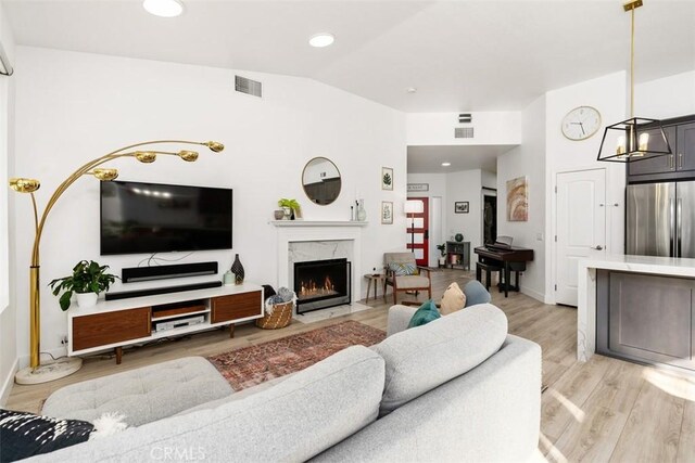 living room featuring light hardwood / wood-style floors, lofted ceiling, and a fireplace