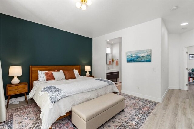 bedroom with ensuite bath and light hardwood / wood-style flooring