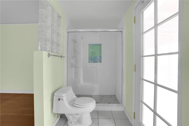 bathroom featuring a shower with shower door, tile patterned flooring, and toilet