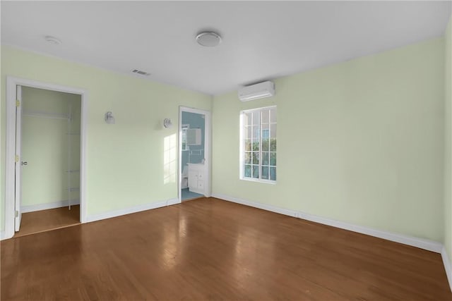 empty room with wood-type flooring and a wall mounted air conditioner