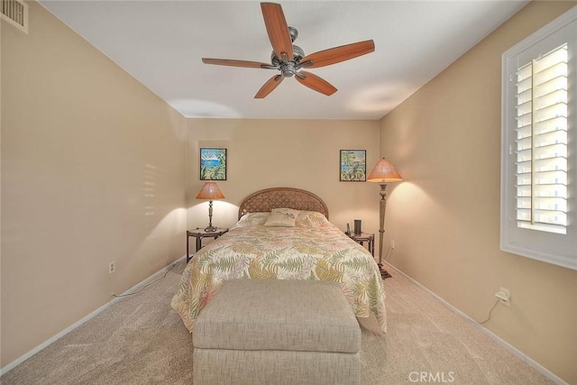 bedroom with ceiling fan, light colored carpet, and multiple windows